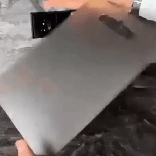 Person chopping vegetables on a titanium cutting board with a chef's knife, highlighting the sleek, double-sided surface.