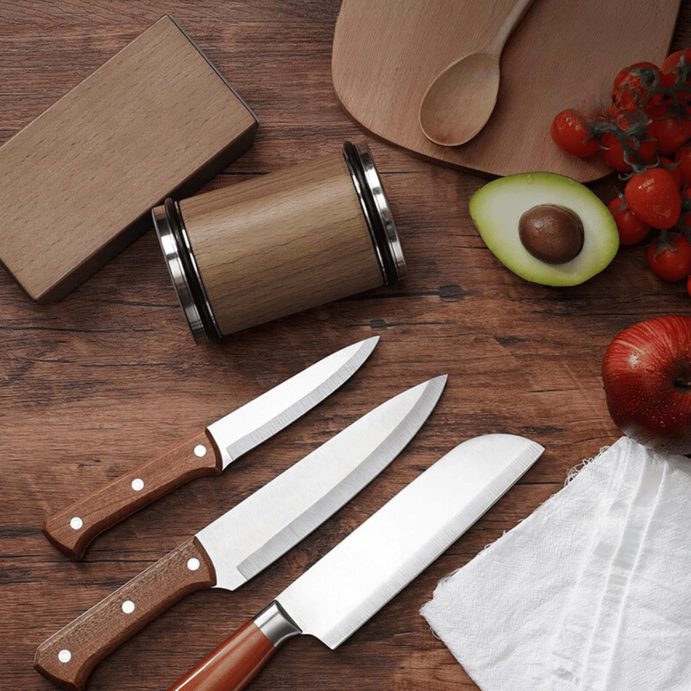 Magnetic rolling knife sharpener placed next to various kitchen knives on wooden countertop
